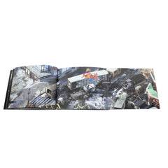 Open book displaying a panoramic aerial photograph of an urban disaster scene.