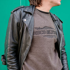Black leather jacket worn over a gray t-shirt with ’DISCO FLY’ printed on it.